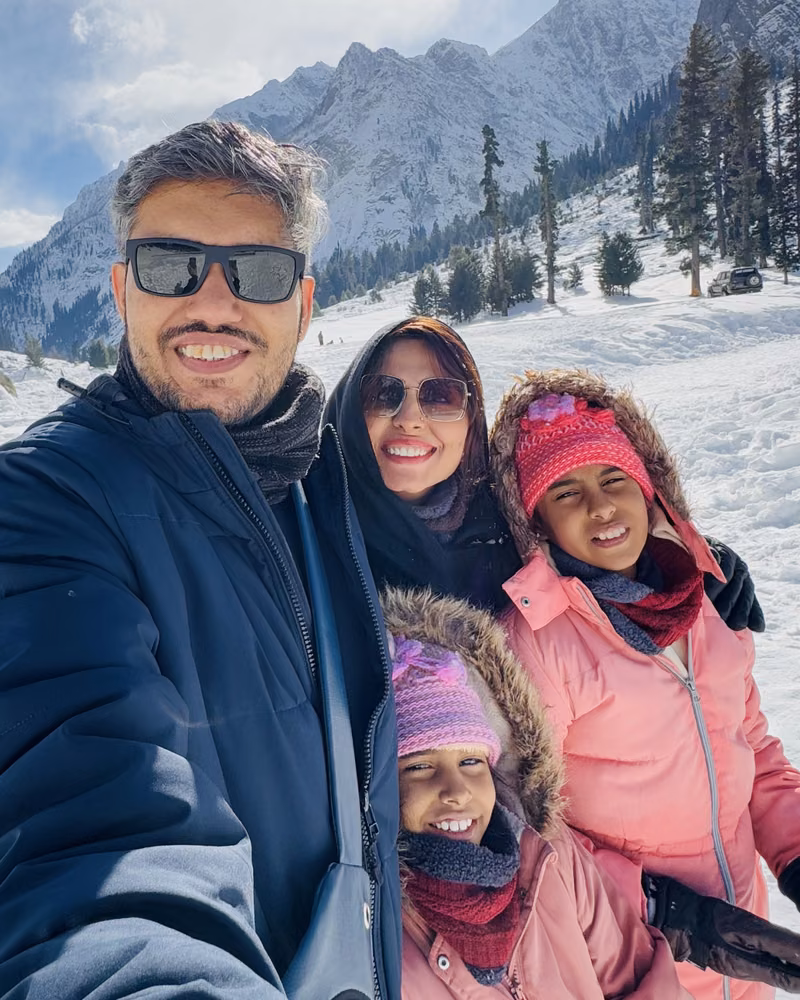 Zair with his family in the snow, mountains behind them